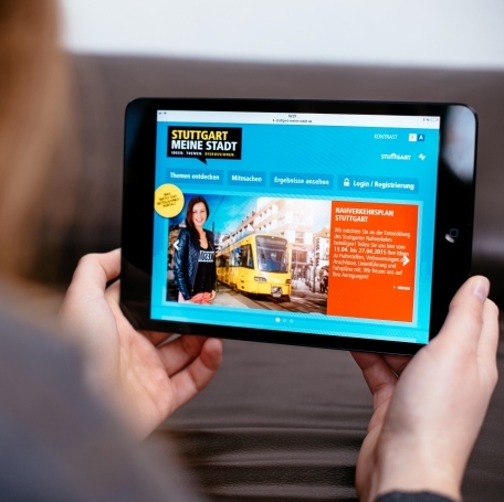 Bild: Eine Frau hält ein Tablet mit beiden Händen. Das Tablet zeigt das Online-Portal. Foto: martinlorenz.net