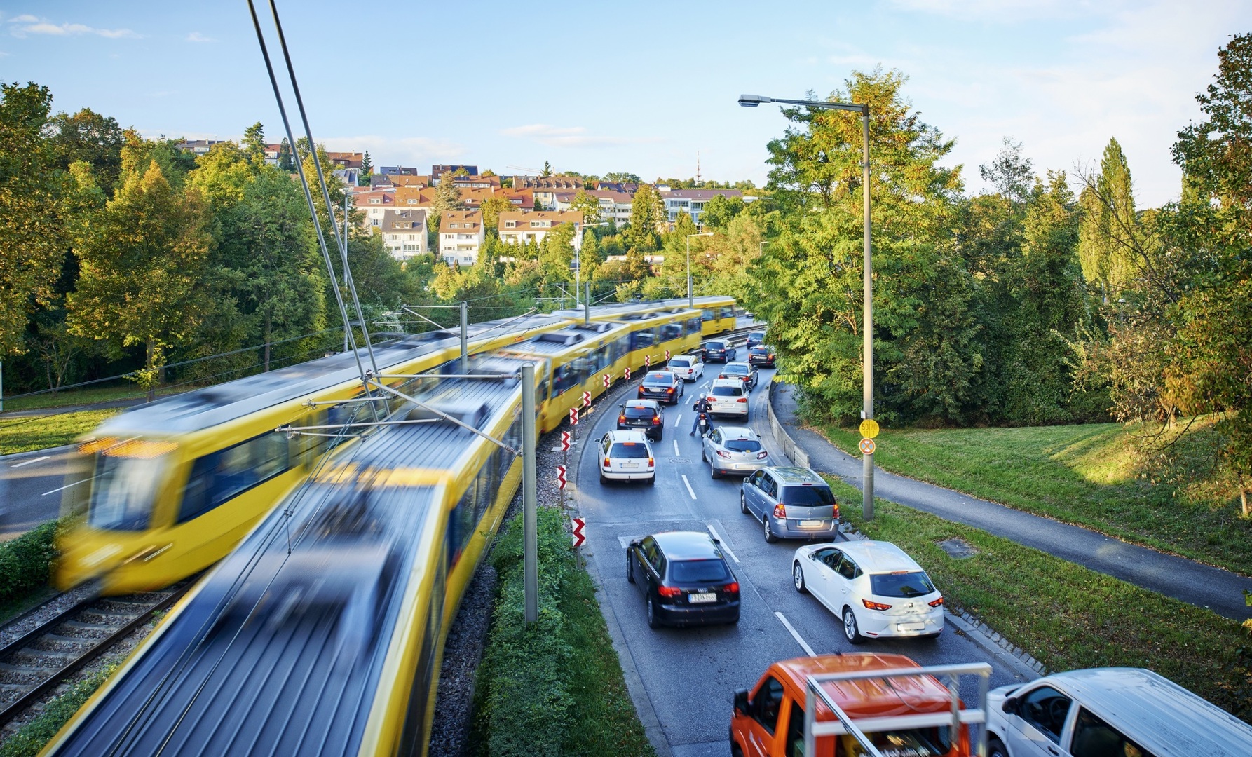 Autos stehen im Stau. Daneben fährt die Stadtbahn am Stau vorbei.