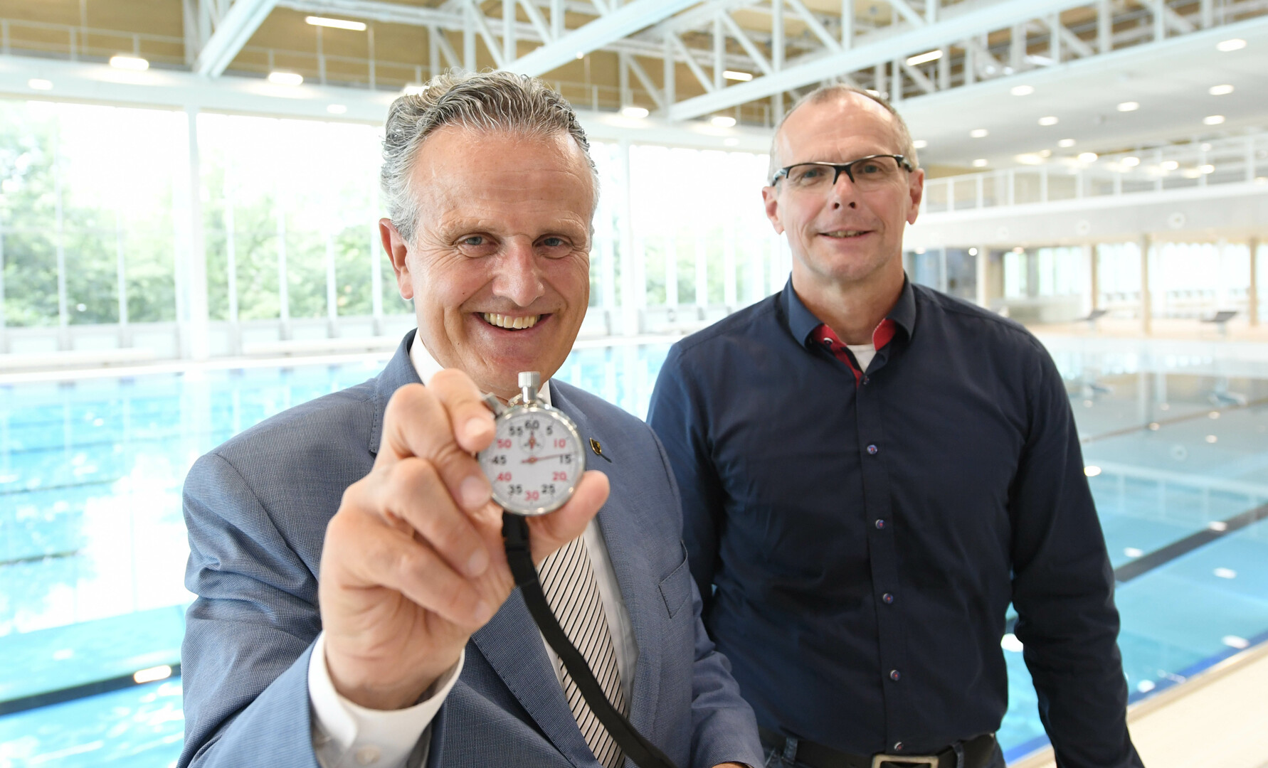 OB Nopper und BM Thürnau stehen vor dem Wasserbecken im neuen Sportbad. Der OB hält eine Stoppuhr in der Hand. Foto: Franziska Kraufmann/Stadt Stuttgart