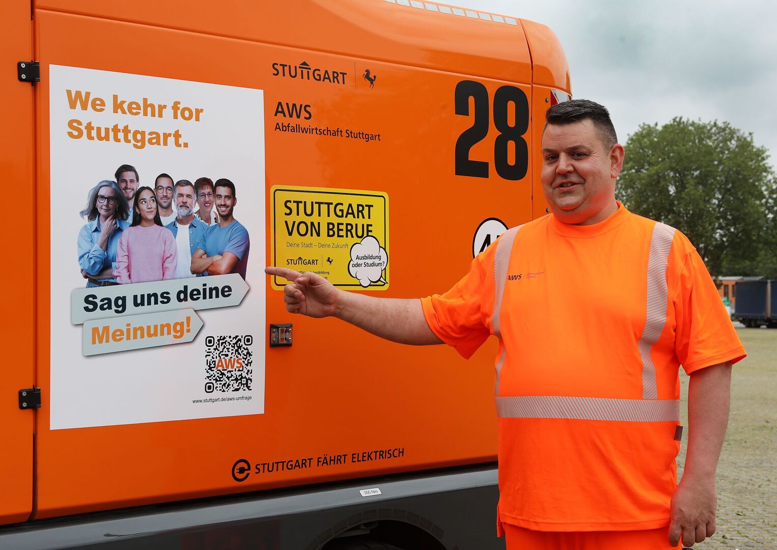 Ein Müllwerker steht vor einem Abfalltransporter und zeigt auf ein an dem Fahrzeug angebrachtes Plakat. Foto: Thomas Hörner/Stadt Stuttgart