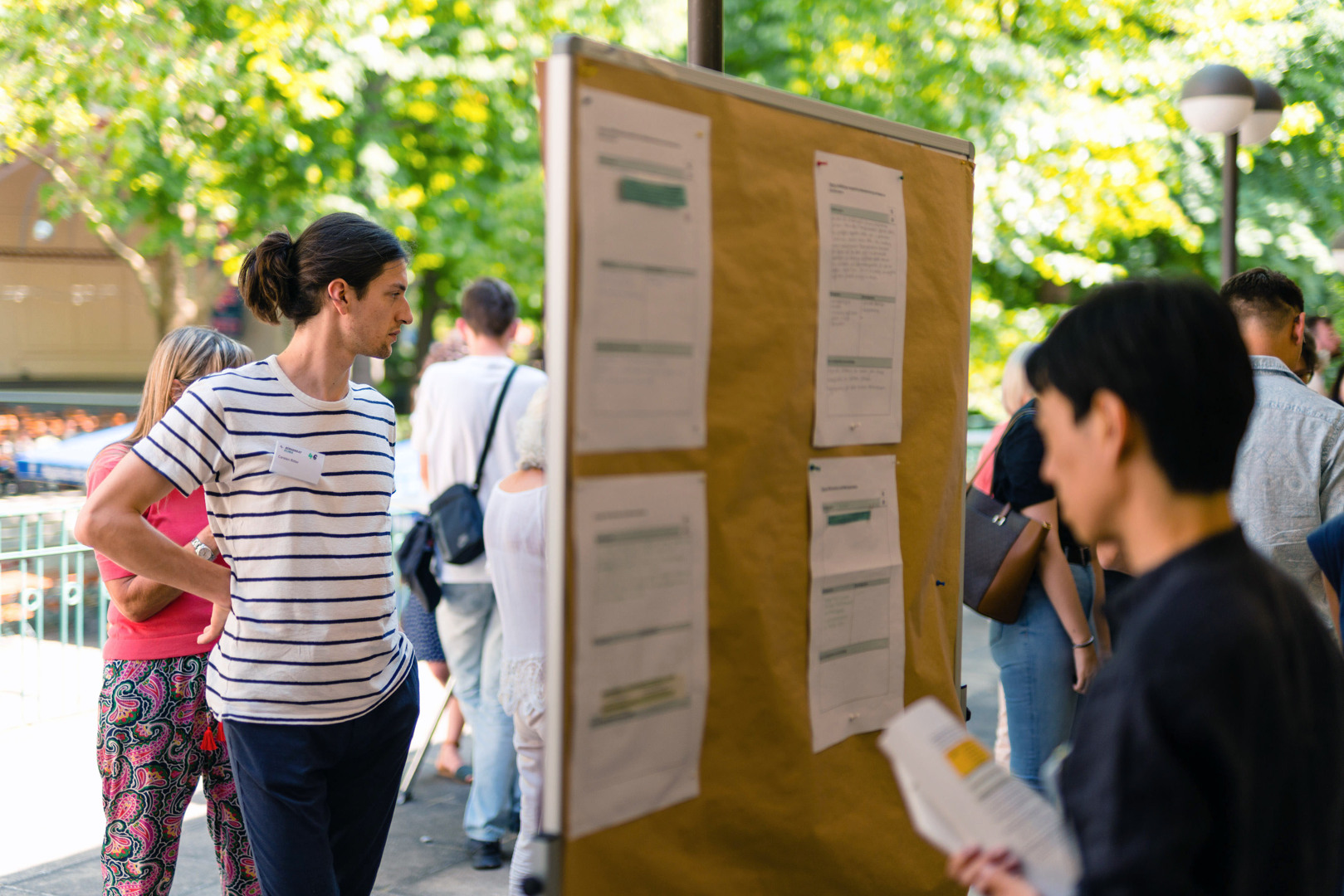 Vor einer STellwand auf einem Platz stehen Menschen und schauen sich die Informationen auf der Wand an. Foto: Ludmilla Parsyak/Stadt Stuttgart
